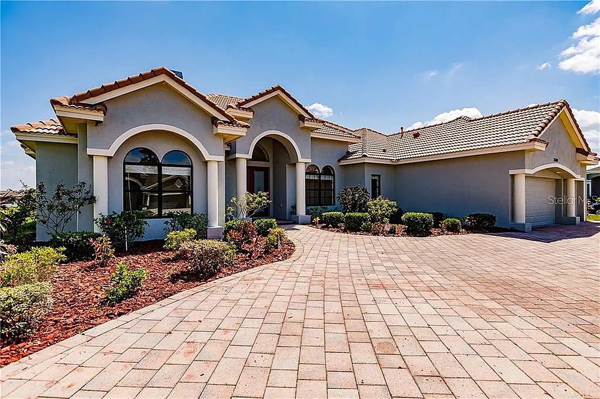 Landscaped Tampa, FL front yard with fresh sod, stone retaining wall and paver walkway by Ideal Landscapes & Hardscaping